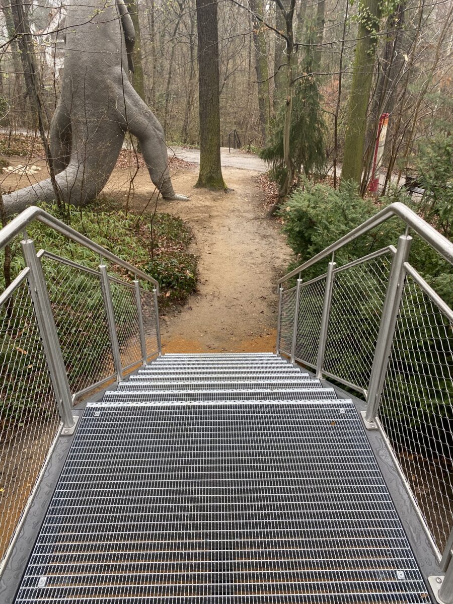 Zugangstreppe im Saurierpark mit pulverbeschichteten Stahlwangen und Edelstahlgeländer mit Seilnetzfüllung, gefertigt von Edelstahlverarbeitung Schmitt.