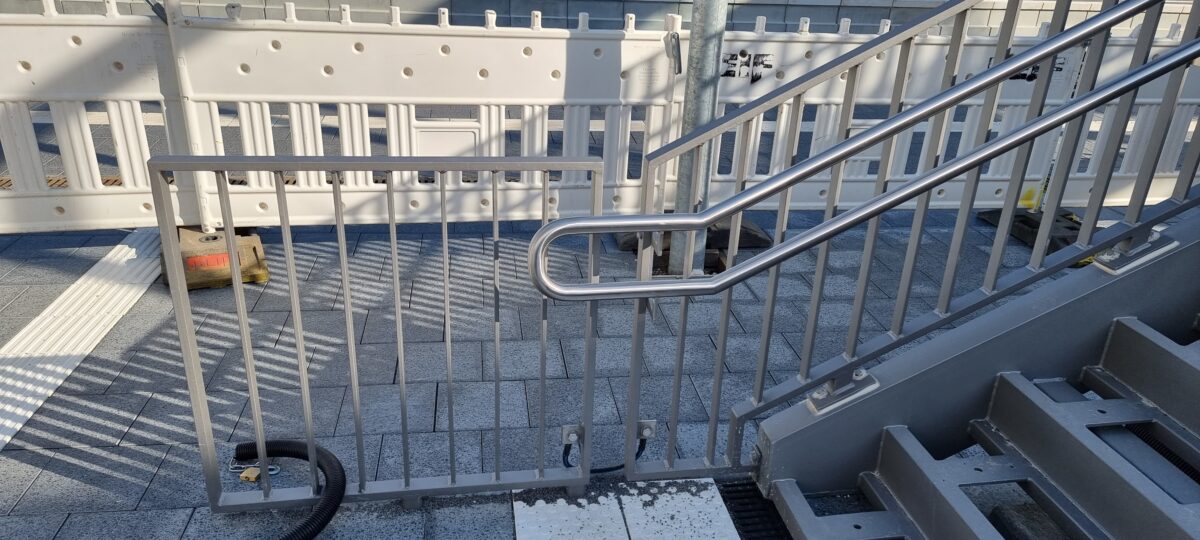 Doppelhandläufe aus Edelstahl mit gebogenen Endstücken und Befestigungsplatten an Bahnbrücken‑Stahlgeländer – gefertigt von Edelstahlverarbeitung Schmitt.