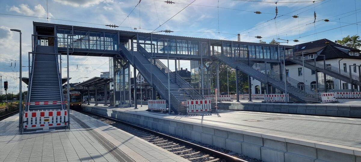 Doppelhandläufe aus Edelstahl mit gebogenen Endstücken und Befestigungsplatten an Bahnbrücken‑Stahlgeländer – gefertigt von Edelstahlverarbeitung Schmitt.