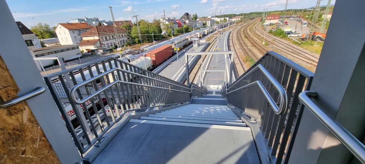 Doppelhandläufe aus Edelstahl mit gebogenen Endstücken und Befestigungsplatten an Bahnbrücken‑Stahlgeländer – gefertigt von Edelstahlverarbeitung Schmitt.