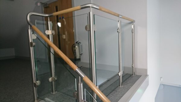 Edelstahl‑Treppengeländer mit Glasfüllung und Holzhandlauf bei Rolawn Limited in York, gefertigt von Edelstahlverarbeitung Schmitt.