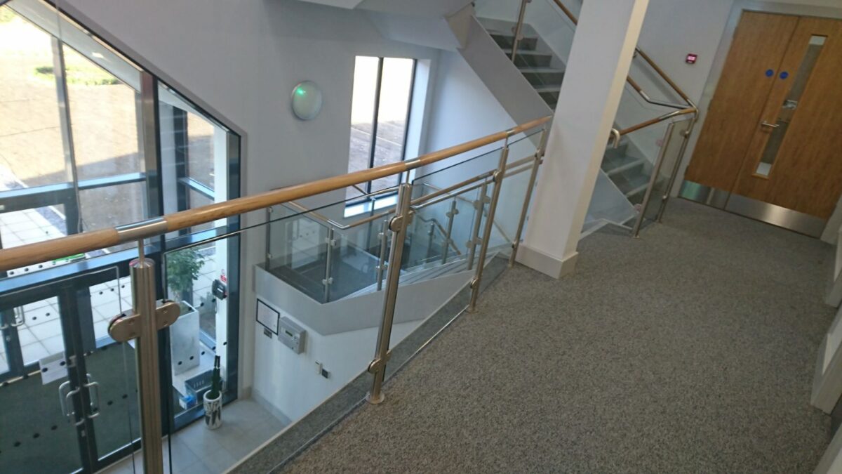 Edelstahl‑Treppengeländer mit Glasfüllung und Holzhandlauf bei Rolawn Limited in York, gefertigt von Edelstahlverarbeitung Schmitt.
