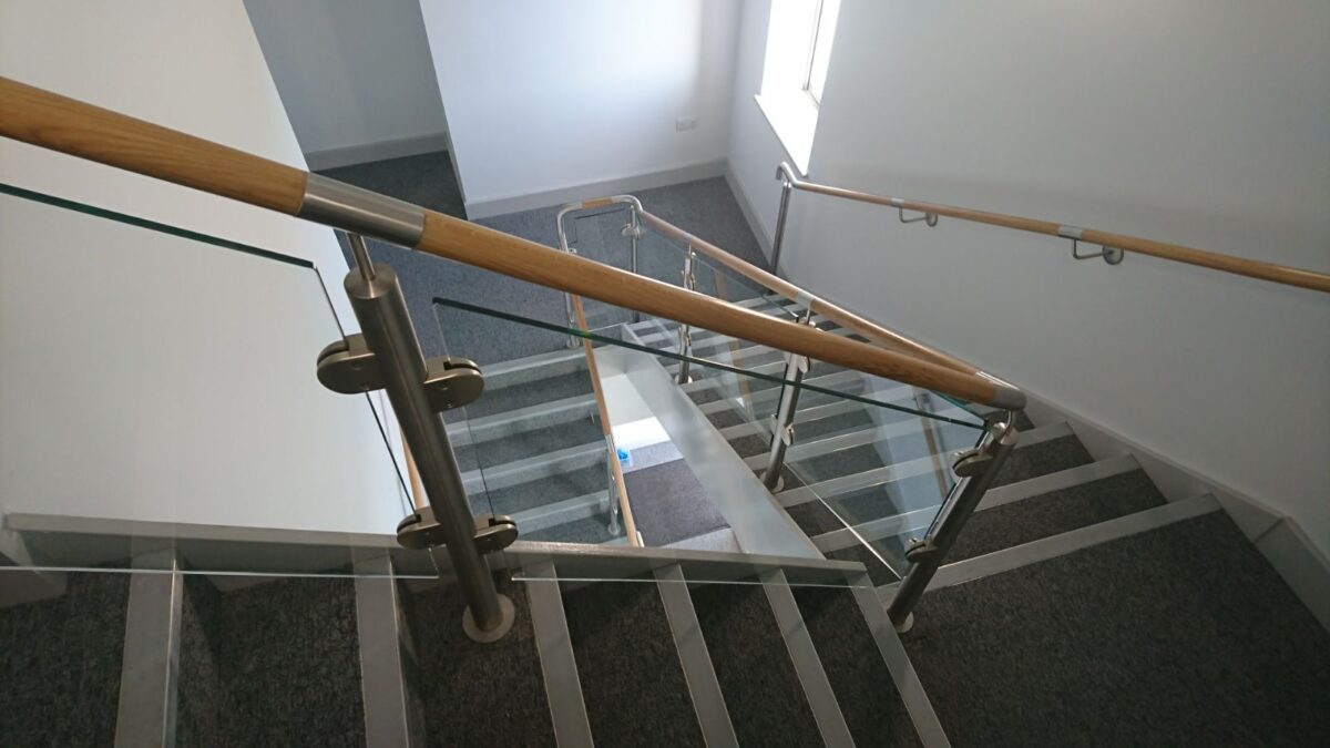 Edelstahl‑Treppengeländer mit Glasfüllung und Holzhandlauf bei Rolawn Limited in York, gefertigt von Edelstahlverarbeitung Schmitt.