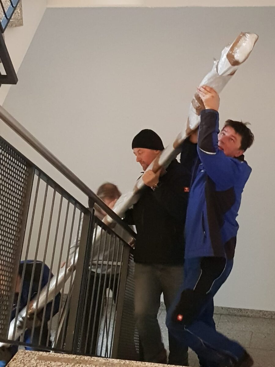Halbgewendelte Edelstahlwangentreppe mit Holzstufen und Füllstabgeländer – gefertigt von Edelstahlverarbeitung Schmitt aus Sohland/Spree für ein Geschäftsgebäude in Leipzig.
